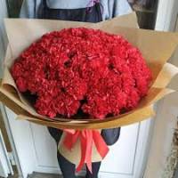 Букет из 29 красных гвоздик в крафте